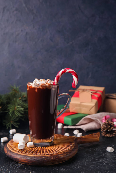 Copa de cristal de sabroso chocolate caliente con malvaviscos y bastón de caramelo sobre fondo negro - Foto, imagen