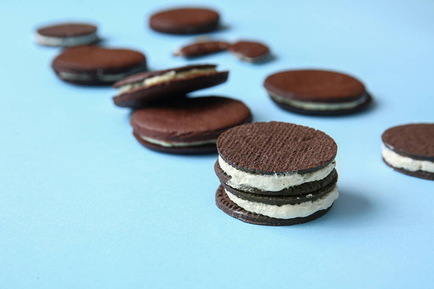 Tasty chocolate cookies with cream on blue background, closeup - Zdjęcie, obraz