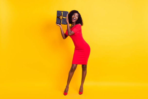 Full body photo of young black girl happy positive smile shake present gift look empty space isolated over yellow color background - Foto, immagini