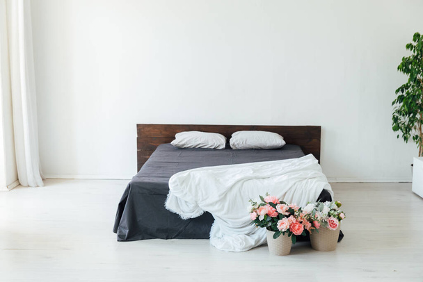 interior of a white bedroom with a bed and flowers - Foto, afbeelding