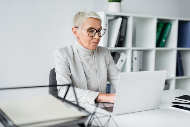 senior businesswoman in glasses working on laptop in office  - Fotó, kép