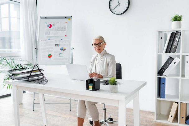 businesswoman with grey hair using laptop in modern office  - Foto, imagen