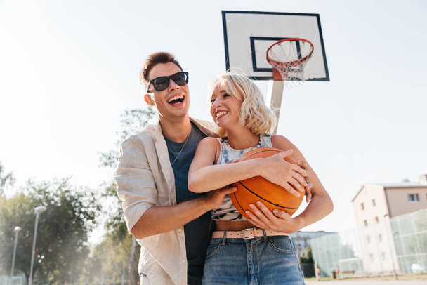 happy couple playing on basketball on playground - Foto, imagen