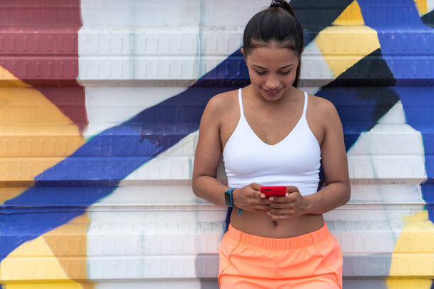 Young woman with her smartphone before running. Healthy living concept. - Foto, Imagen