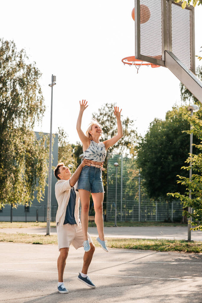 happy couple playing on basketball on playground - 写真・画像