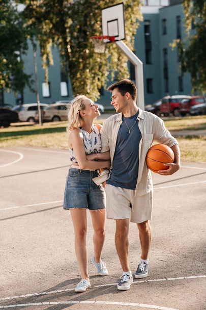 happy couple with ball on basketball playground - Fotografie, Obrázek