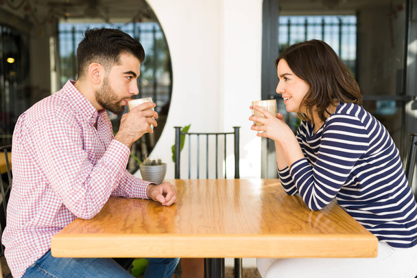 Çekici bir çift ilk buluşmaya çıkıyor ve kahve içiyor. Genç bir kadın ve erkek bir kahve dükkanında konuşuyor ve flört ediyorlar. - Fotoğraf, Görsel