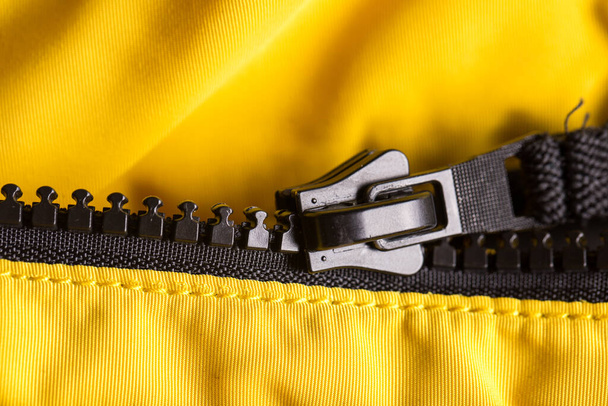 Zipper on clothes close-up. black color. Bright yellow jacket - Photo, image