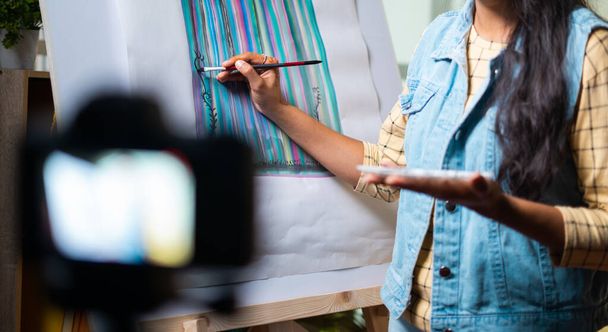 αγνώριστη καλλιτέχνης κορίτσι διδασκαλία ζωγραφική καμβά καταγράφοντας στην κάμερα - έννοια της online διδασκαλίας, εικονική τάξη ή εκπαίδευση κατά τη διάρκεια coronavirus covid-19 πανδημία - Φωτογραφία, εικόνα