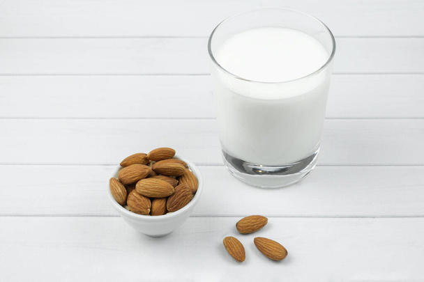 White ceramic bowl with almonds and and a glass of milk. Alternative milk concept, food for allergy sufferers and vegetarians. Health care. - Zdjęcie, obraz