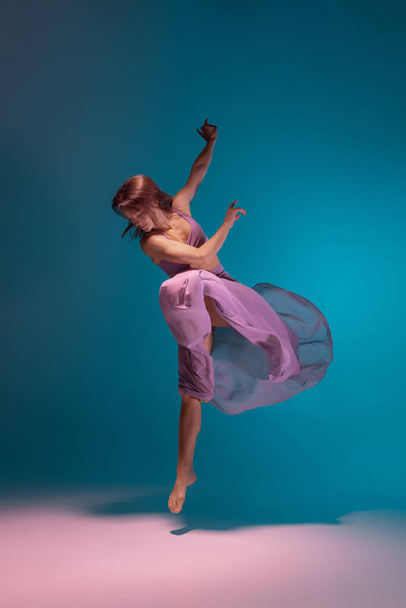 One young flexible contemp dancer in lilac dress dancing isolated on gradient blue white background in neon. - Fotografie, Obrázek