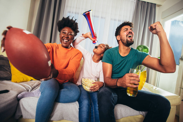 Οικογενειακή βλέποντας αμερικανικό ποδοσφαιρικό αγώνα στην τηλεόραση στο σπίτι - Φωτογραφία, εικόνα