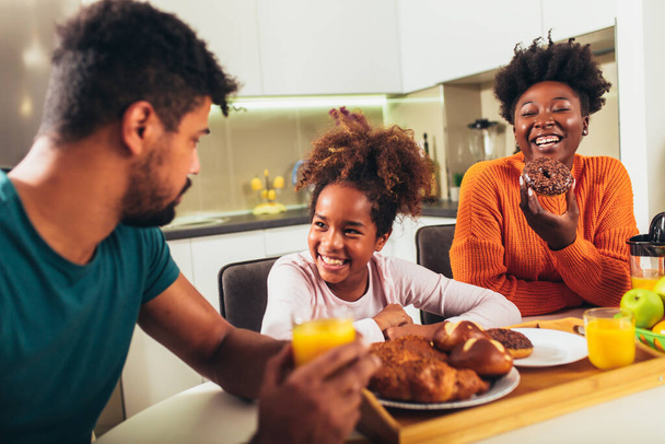 Familia en casa desayunando en la cocina juntos, divirtiéndose. - Foto, Imagen