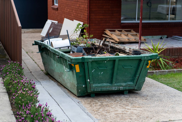 Скип мусорный бак с бытовыми отходами на переднем дворе. Концепция ремонта. - Фото, изображение
