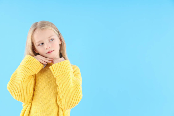 Cute little girl in sweater on blue background - Фото, зображення