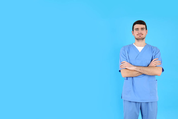 Νεαρή ελκυστική αρσενική νοσοκόμα σε μπλε φόντο - Φωτογραφία, εικόνα