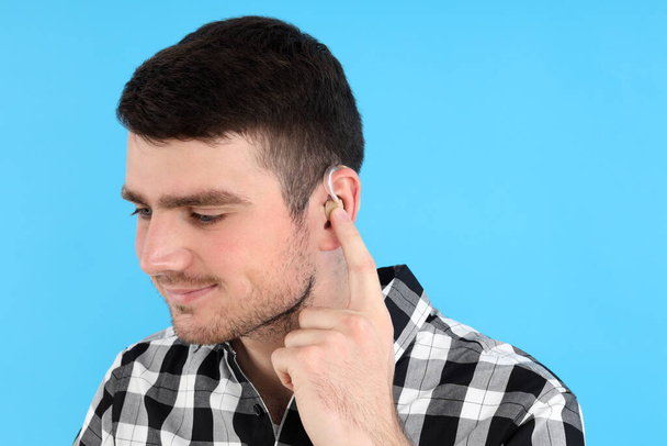 Νεαρός με ακουστικό βαρηκοΐας σε μπλε φόντο - Φωτογραφία, εικόνα