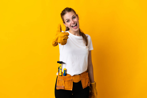 Mujer electricista joven aislada sobre fondo amarillo con pulgares hacia arriba porque algo bueno ha sucedido - Foto, imagen