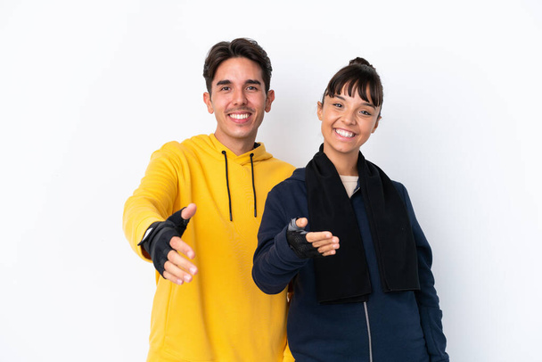 Young mixed race sport couple isolated on white background shaking hands for closing a good deal - Foto, imagen