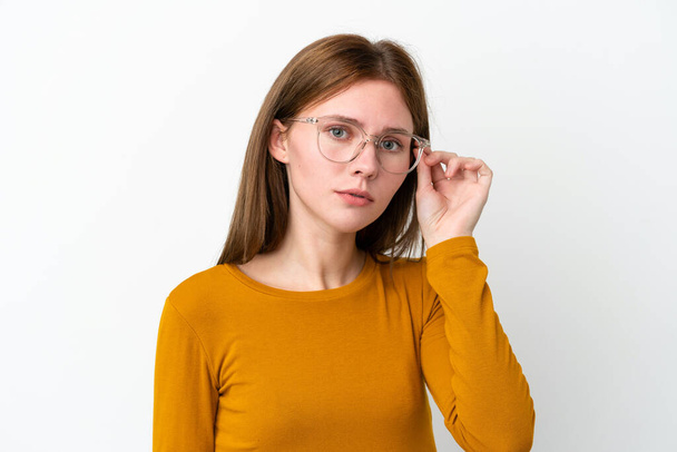 Молода англійська жінка, ізольована на білому тлі з окулярами й роздратованим виразом обличчя. - Фото, зображення