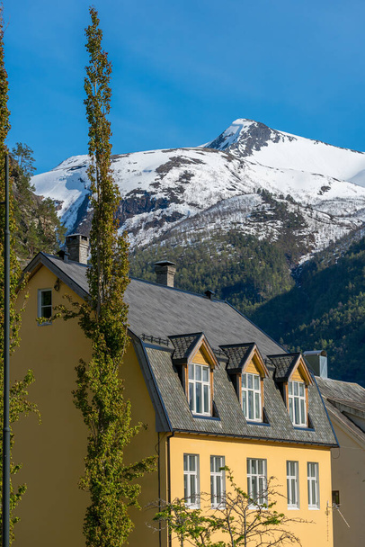 VALLDAL, NORWEGEN - 2020 29. Mai. Dorfhaus im Valldalen mit Bergen mit Schnee im Hintergrund. - Foto, Bild