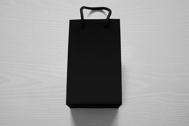 Lujoso bolso de compras negro mate contra madera blanca desde arriba - Foto, Imagen