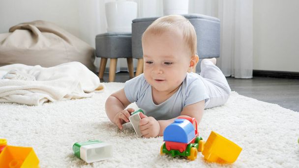 Evdeki yumuşak halıda oyuncaklarla oynayan tatlı bir bebek. Çocuk eğitimi ve gelişimi - Fotoğraf, Görsel