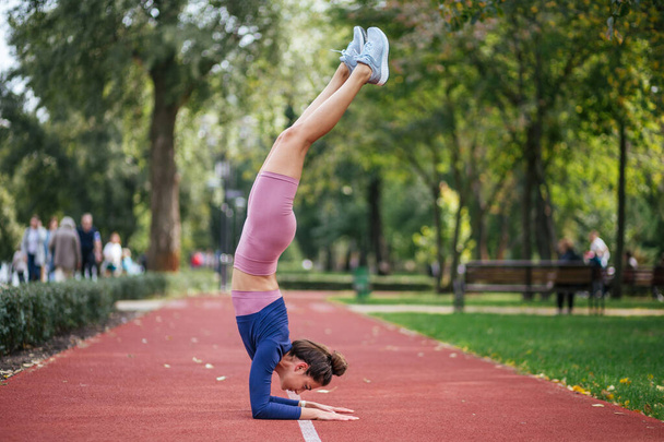 mooi meisje doet yoga poseert op de zonsondergang in het park, evenwicht, fitness, stretching en ontspanning - Foto, afbeelding