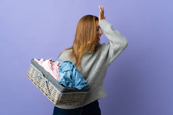 Middle age woman holding a clothes basket isolated on purple background has realized something and intending the solution - 写真・画像
