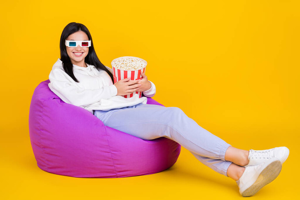 Full size photo of millennial lady sit bean chair hold pop corn basket isolated over shine yellow color background - Fotoğraf, Görsel