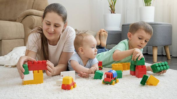 明るい赤ん坊、男の子と母親が自宅でカーペットの上でおもちゃを駐車笑顔。家族の時間と子供の発達の概念 - 写真・画像