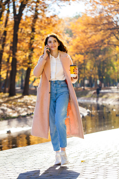 Young beautiful business woman making a cell phone call in autumn park - Foto, Imagen