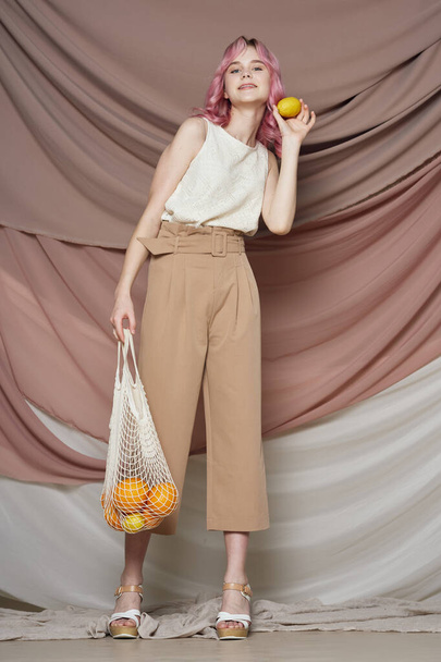 woman with pink hair pack with oranges posing fashion - 写真・画像