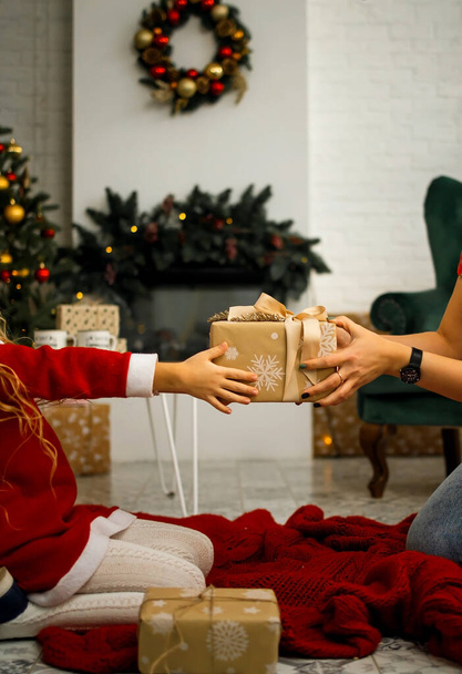 Concepto de celebración navideña. Primer plano de las manos femeninas sosteniendo el regalo y dando regalo caja a mujer, saludo con cumpleaños, Navidad y Año Nuevo en casa - Foto, imagen