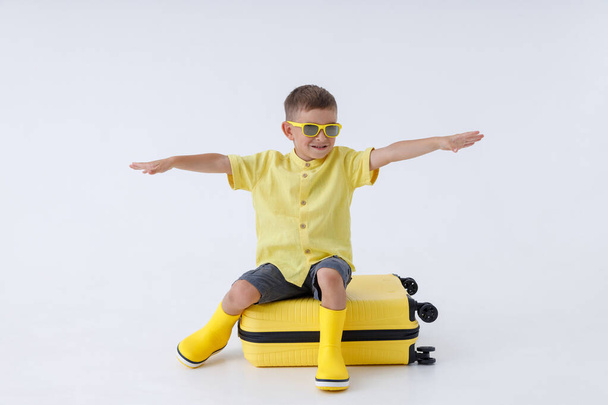 Adorable little boy sitting on yellow travel bag - Photo, Image
