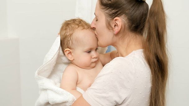 liefhebbende moeder zoenen haar baby zoon na wassen in bad - Foto, afbeelding