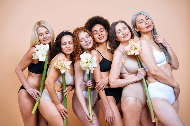 imagem de beleza de um grupo de mulheres com idade diferente, pele e corpo posando no estúdio de um fototiroteio positivo de corpo. Modelos femininos mistos em lingerie em fundos coloridos - Foto, Imagem
