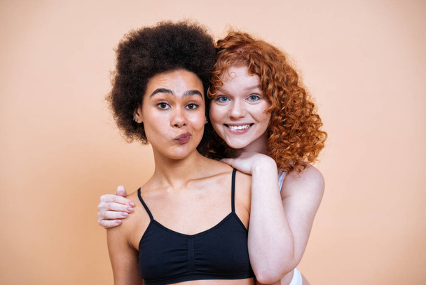 beauty image of two young women with different skin and body posing in studio for a body positive photoshooting. Mixed female models in lingerie on colored backgrounds - Fotó, kép