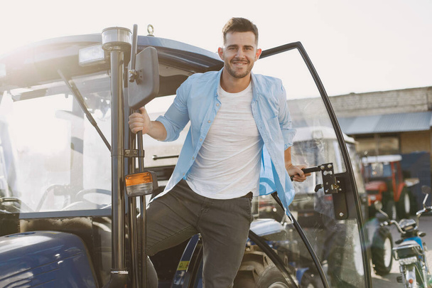 Male standing by the blue tractor - Φωτογραφία, εικόνα