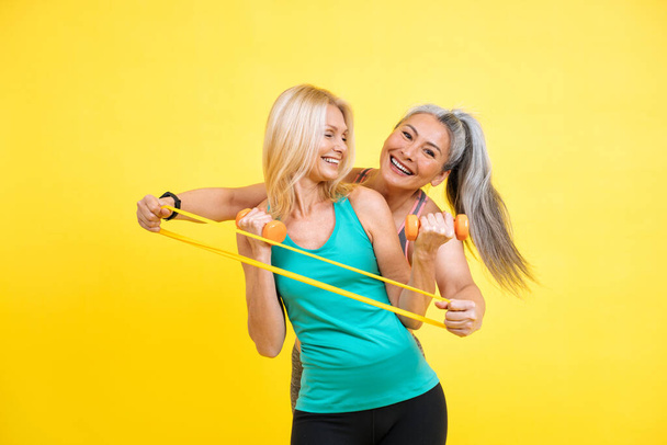 Image of two women with different body, age, and ethnicity making sport. Female models wearing sport outfits having fun at the gym. Concept about body positivity, self acceptance and lifestyle - Foto, Imagen
