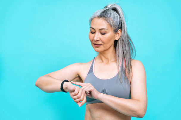 beautiful middle aged woman making sport at the gym.  female model posing for a body positive and self acceptance concept photoshooting on colored backgrounds - Foto, Imagem