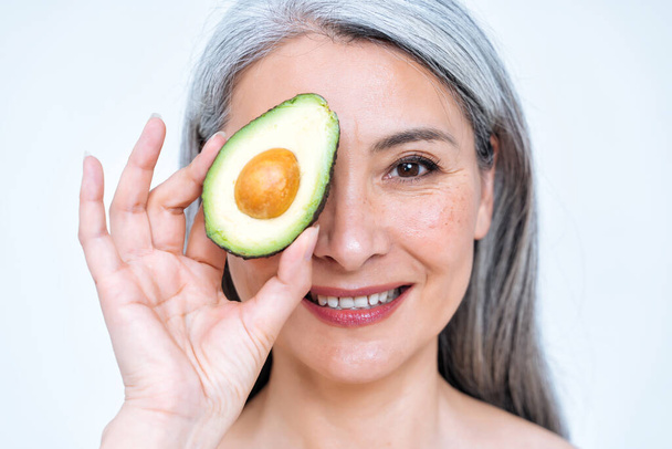 Image of a senior woman posing in studio for a body positive concepts photoshooting. old model showing fruits and healthy food good for the skin care therapy - 写真・画像