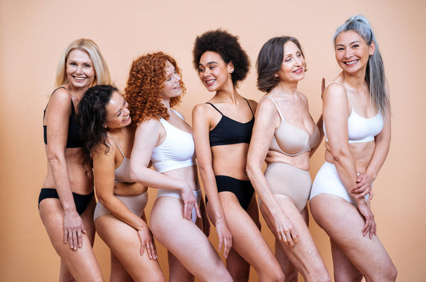 Зображення краси групи жінок різного віку, шкіри та тіла позує в студії для позитивного фотосесії тіла. Змішані жіночі моделі в нижній білизні на кольоровому фоні
 - Фото, зображення