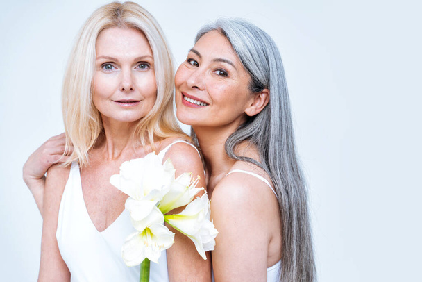 beauty image of two women with different age, skin and body posing in studio for a body positive photoshooting. Mixed female models in lingerie on colored backgrounds - Valokuva, kuva