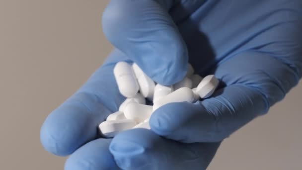 Zbliżenie ręki w gumowych rękawiczkach z białymi tabletkami. - Materiał filmowy, wideo
