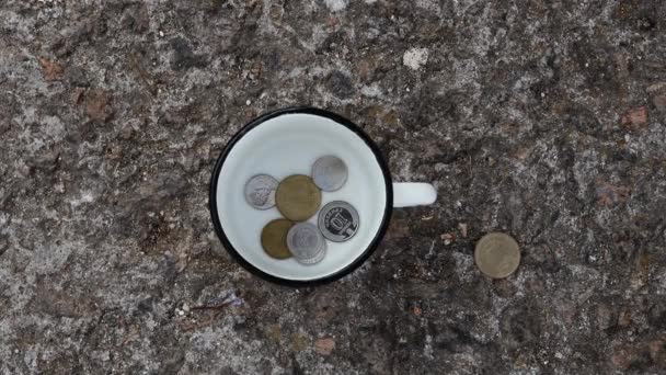 Distribuzione di monete a un mendicante. Moneta moneta in vaso di metallo su fondo grigio, donazione, risparmio, raccolta fondi di beneficenza. Vista dall'alto. - Filmati, video