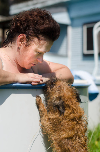 Bir kadın. Havuzun kenarında, bir köpekle iletişim kuruyor - Brüksel Griffin - Fotoğraf, Görsel