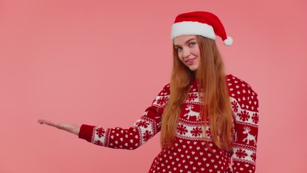 Mulher usa veado vermelho ano novo suéter mostrando polegares para cima e apontando para no espaço de publicidade em branco - Filmagem, Vídeo