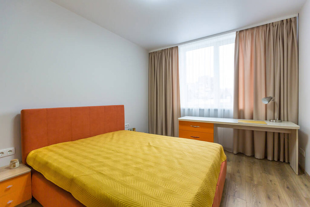 Interior de una habitación con una cama naranja y un sofá de estilo moderno - Foto, imagen