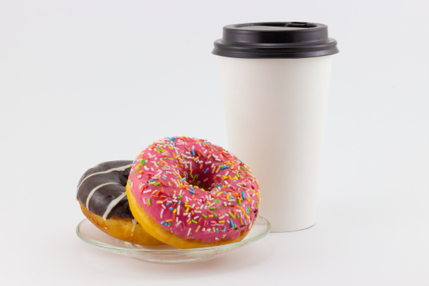 Stillleben mit bunten Donuts auf Teller und Kaffeetasse aus Papier auf weißem Hintergrund. Weiße Einweg-Pappbecher zum Mitnehmen mit Kopierraum - Foto, Bild